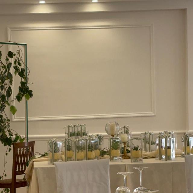 Elegante tavola apparecchiata con dettagli verdi e candele, ambiente raffinato e accogliente.