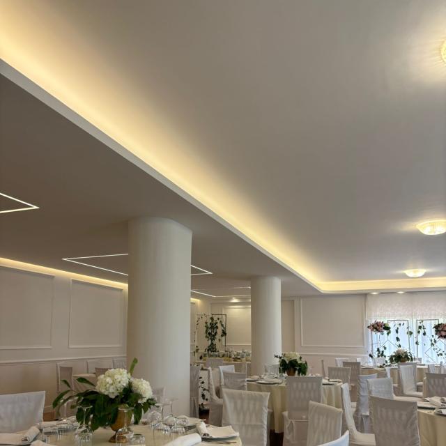 Sala elegante con tavoli rotondi, fiori bianchi e atmosfera raffinata.