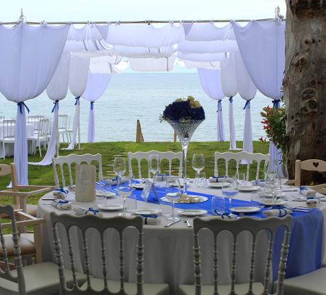 Elegant outdoor tables with sea view and blue decorations.