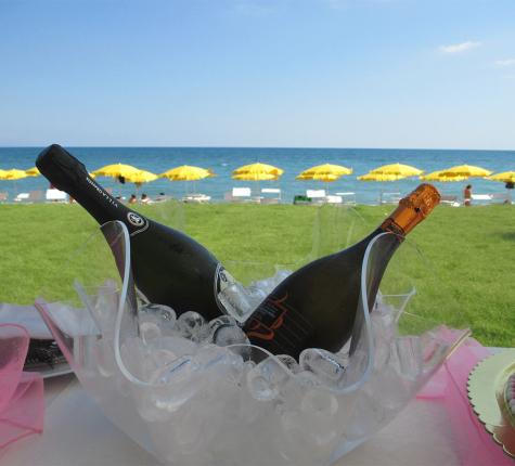 Champagne bottles in ice, beach with yellow umbrellas in the background.