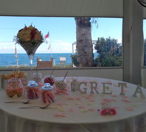 Decorated table with sweets and flowers, sea view.