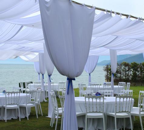 Elegant marquee with white tables overlooking the sea.
