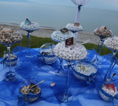 Sugared almonds displayed in elegant bowls on a blue table, sea view.