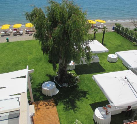 Garden with white gazebos near the beach, yellow umbrellas in the background.