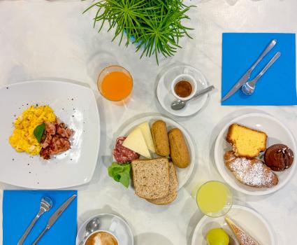 Colazione ricca: uova, dolci, frutta, caffè e succhi su tavola elegante.