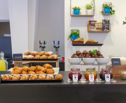 Buffet di dolci invitanti: croissant, muffin, marmellate e yogurt, atmosfera accogliente.