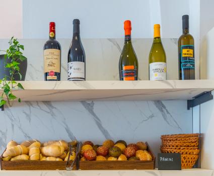 Scaffali con pane e vini, atmosfera accogliente e rustica.