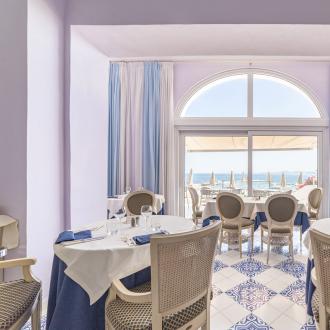 Elegant seaside restaurant with set tables and refined decor.