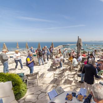 Group of people on terrace with sea and harbor view.