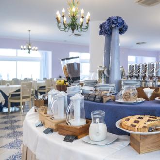 Breakfast buffet with pastries, cereals, and milk in an elegant dining room.