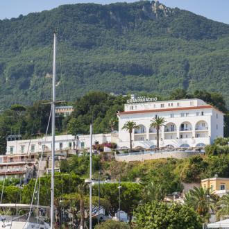 View of a marina with a hotel and mountains in the background.