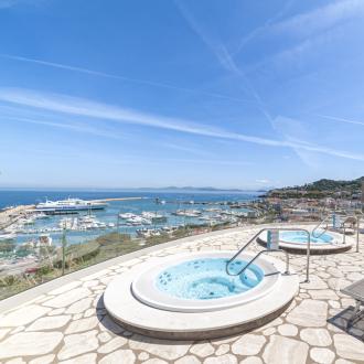 Panoramic view with jacuzzis, sun loungers, and marina.