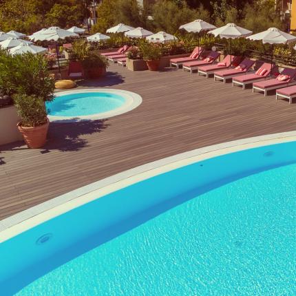 Pool with sun loungers, umbrellas, and a hot tub.