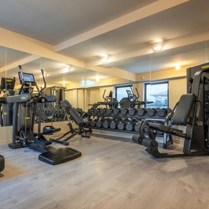 Modern gym with advanced equipment, mirrors, and free weights.