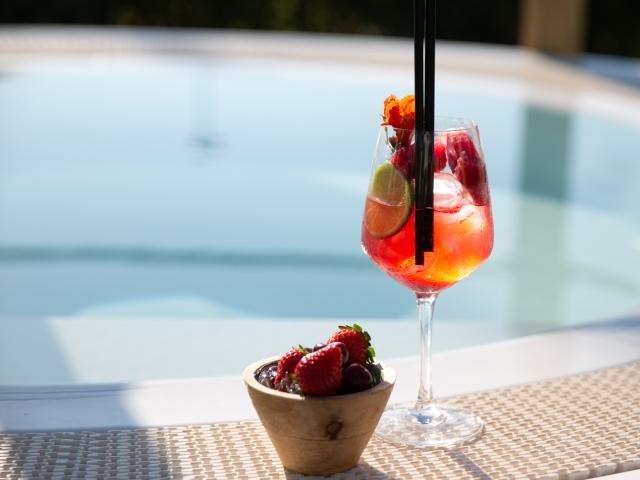 Cocktail estivo con fragole e lime accanto a una piscina.