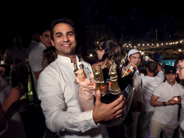 Festa in piscina con champagne e amici in abiti bianchi.