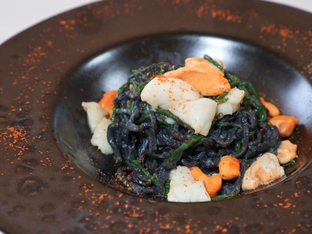 Pasta al nero di seppia con frutti di mare e verdure.