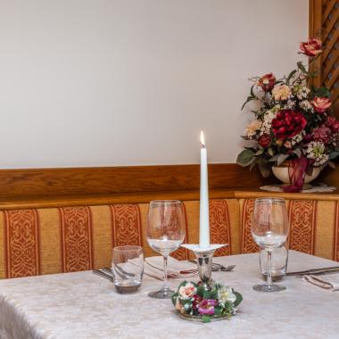 Elegant restaurant table with a lit candle and decorative flowers.