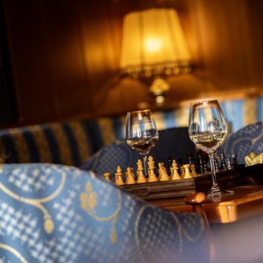 Chessboard with wine glasses and chips in a cozy setting.