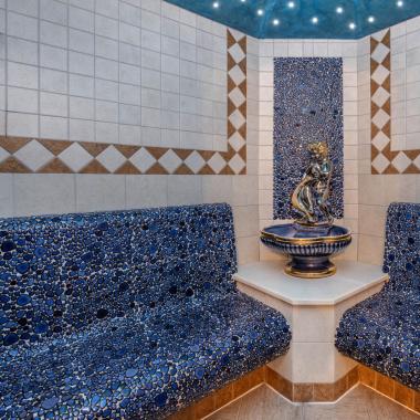 Relaxation room with blue mosaics and central statue.