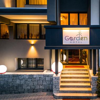 Ingresso illuminato dell'hotel Garden con insegna e gradini.