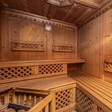 Sauna in legno con panche e termometro a parete.