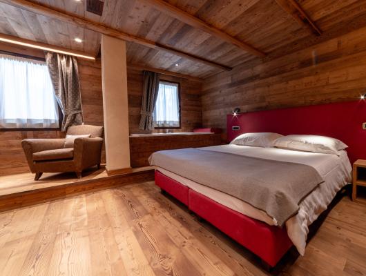 Camera accogliente con letto matrimoniale, poltrona e arredamento in legno.