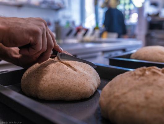 Mani che incidono l'impasto del pane prima della cottura.