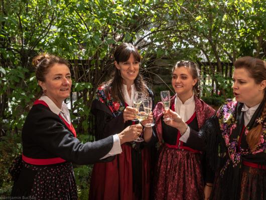 Donne in costumi tradizionali brindano all'aperto.