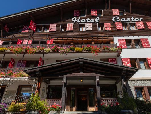 Hotel pittoresco con fiori colorati e finestre con persiane rosse.