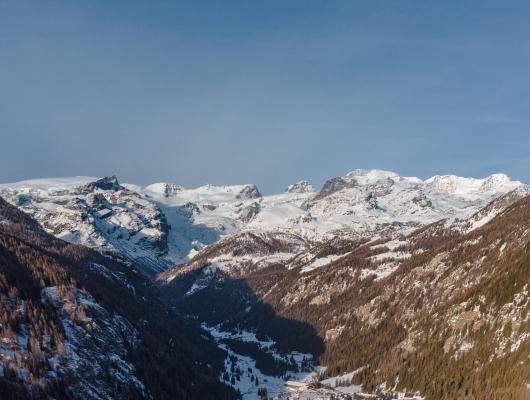 Panorama invernale di un villaggio di montagna con cime innevate.