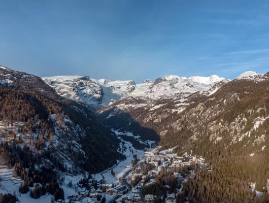 Paesaggio invernale montano con villaggio innevato e montagne sullo sfondo.