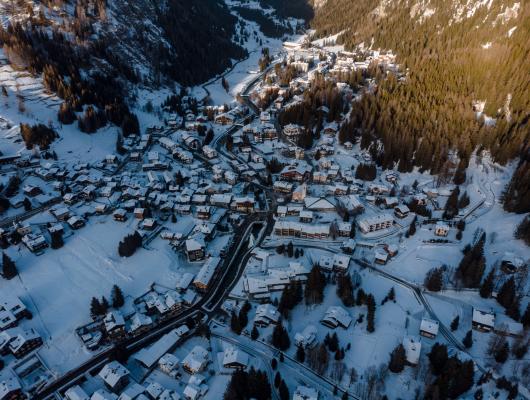 Vista aerea di un villaggio innevato tra le montagne.