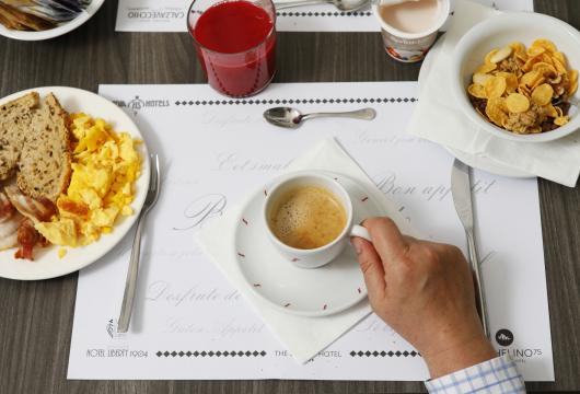 Colazione con caffè, succo, cereali, pane e uova strapazzate.