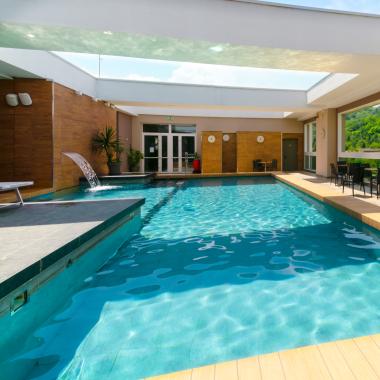 Piscina luminosa con vista colline verdi, atmosfera rilassante e moderna.
