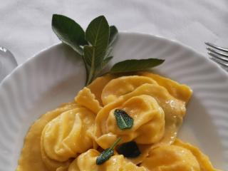 Piatto di tortelloni al burro e salvia su piatto bianco.