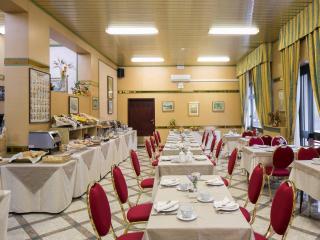 Sala colazione elegante con sedie rosse e tavoli apparecchiati.