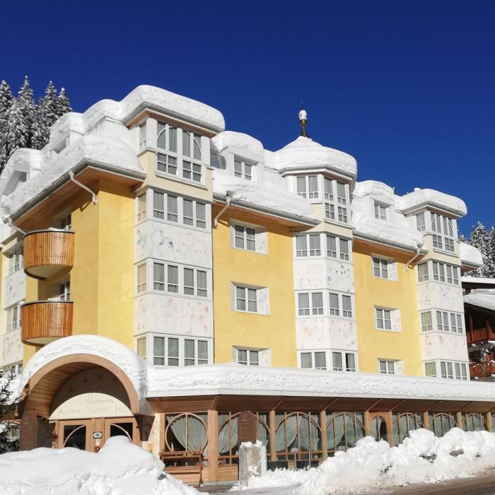 Snowy hotel, bright sun, blue sky, enchanting alpine atmosphere.