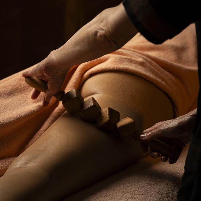 Relaxing massage with wooden roller on warm, soft skin.