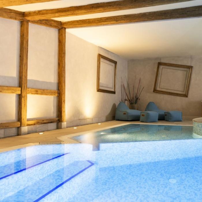 Elegant indoor pool with seating and tilted frames, relaxing and sophisticated atmosphere.