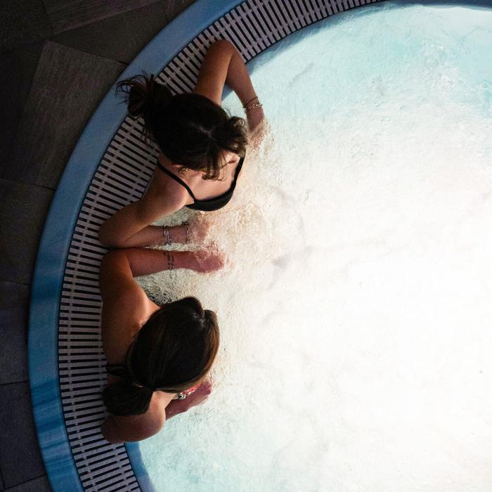 Two people relaxing in a jacuzzi, surrounded by warm bubbling water.