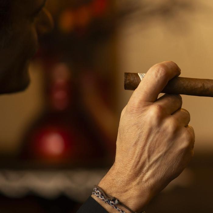 Male hand holding cigar, warm and relaxed atmosphere.