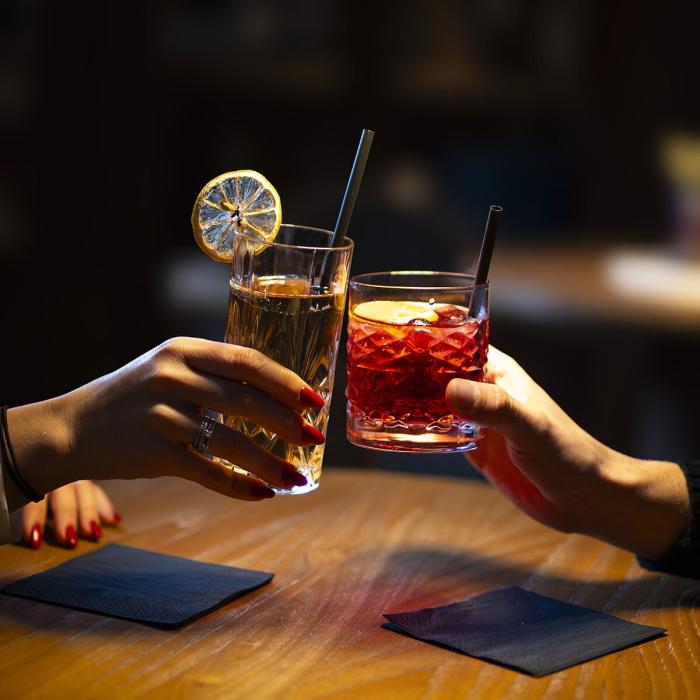 Intimate toast with colorful cocktails, warm atmosphere, and soft lighting.