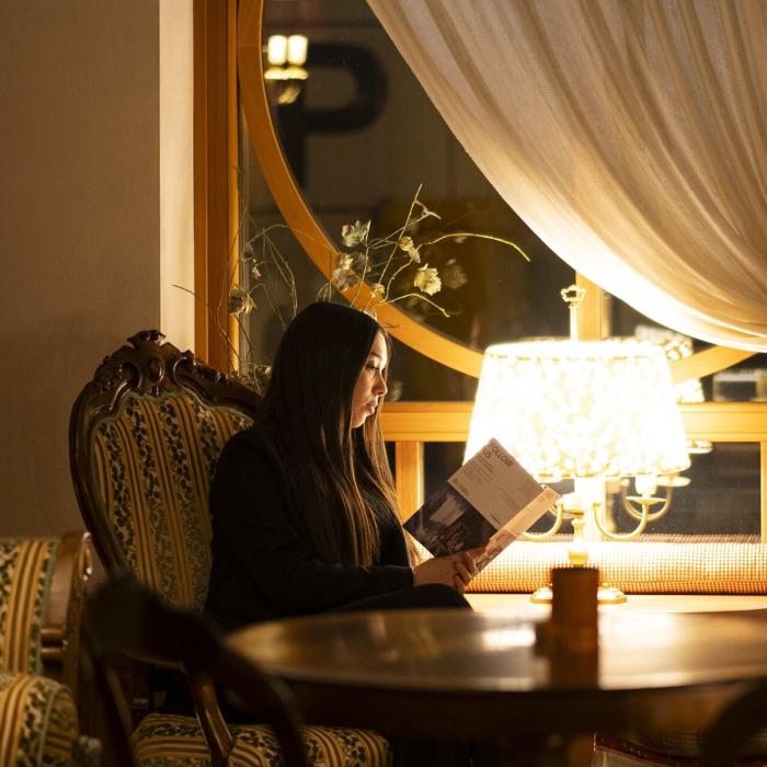 Woman reading in elegant lounge, warm and relaxing atmosphere.