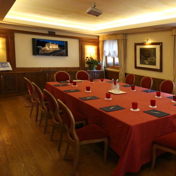 Elegant meeting room with red table, cozy chairs, and warm lighting.