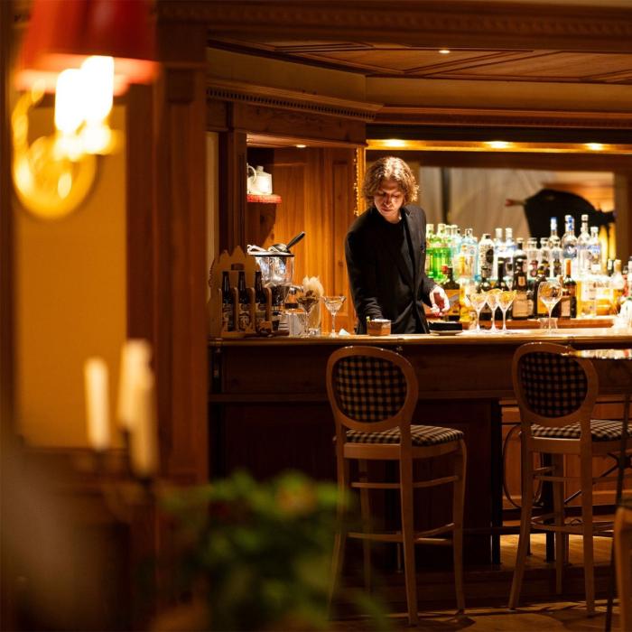 Cozy bar with soft lighting and elegant bartender, warm and intimate atmosphere.