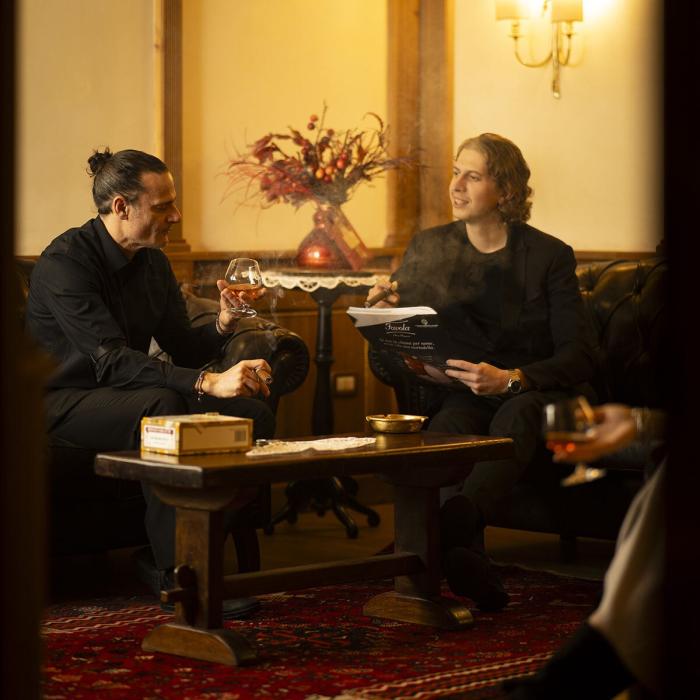 Two elegant men smoking cigars, warm and relaxed atmosphere.