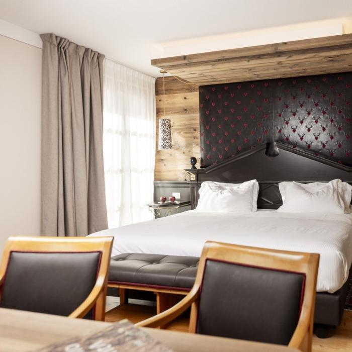 Elegant room with cozy bed, warm wood, and soft lighting.