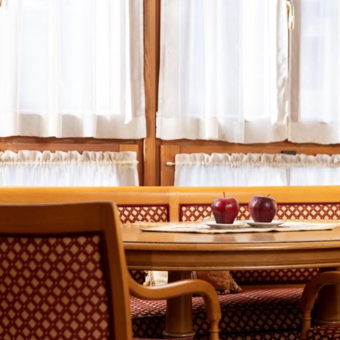 Cozy table with red apples, warm light, and white curtains.