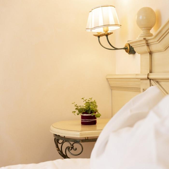 Cozy room with soft bed, warm lamp, and plant on the nightstand.